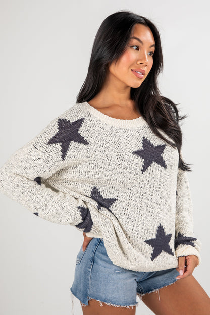 Woman wearing a white sweater with star patterns on a plain background