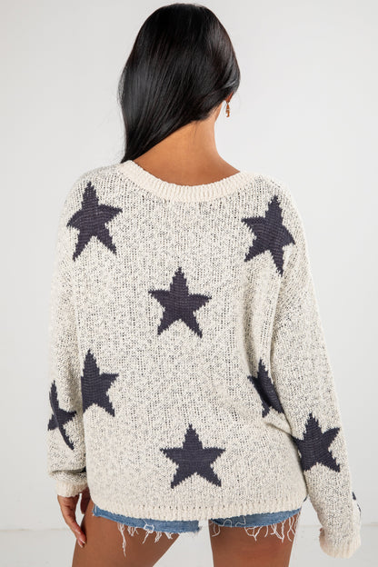 Person wearing a cream sweater with black star patterns on a white background