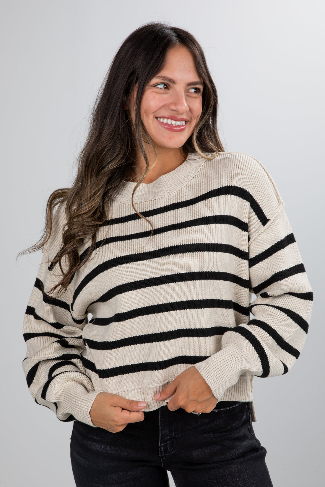 Woman wearing a black and white striped sweater against a plain background