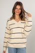 Woman wearing a cream and black striped sweater against a plain background