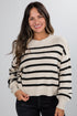 Woman wearing a cream and black striped sweater against a plain background