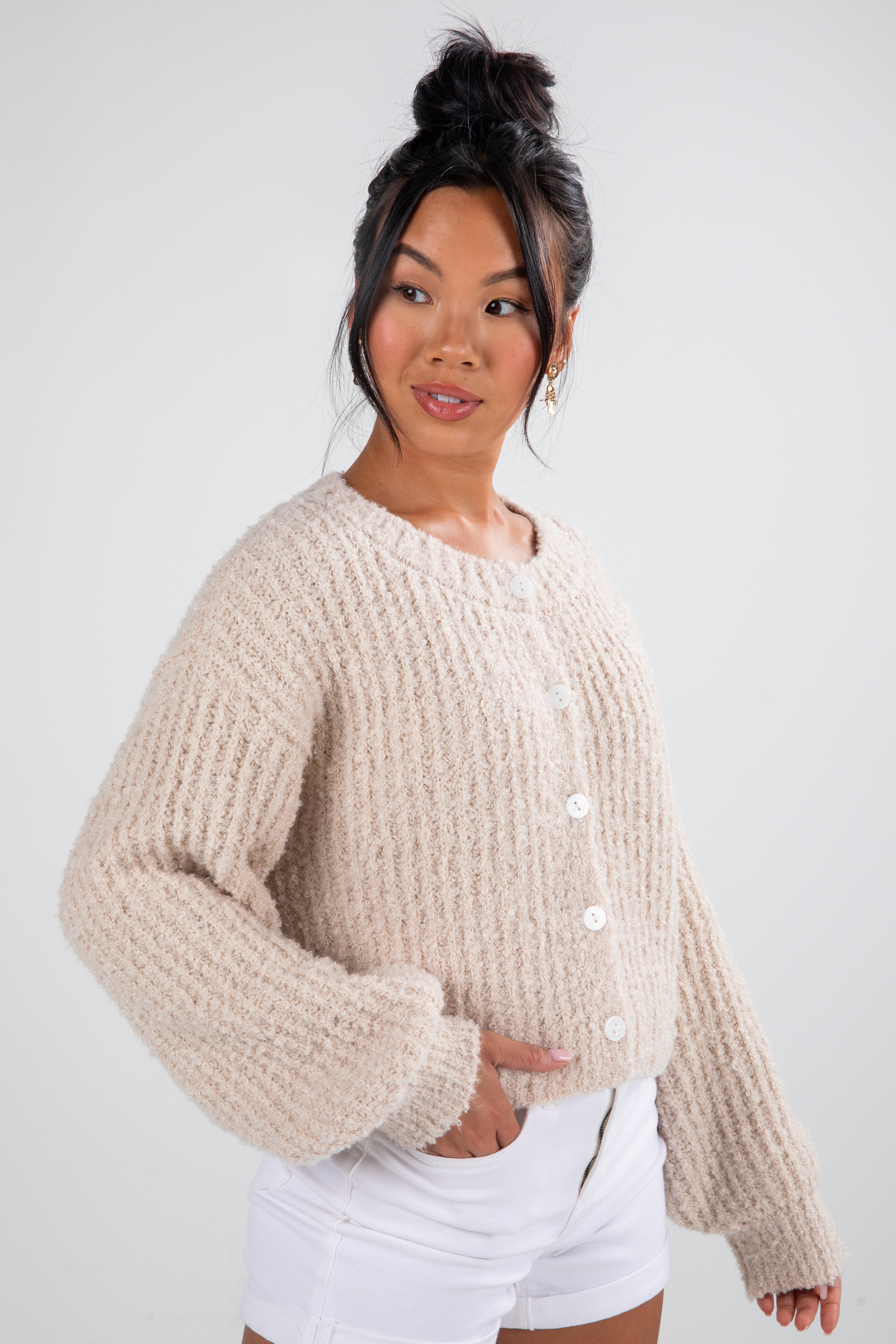 Woman wearing a beige knitted cardigan against a white background