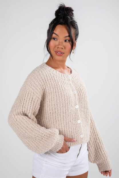 Woman wearing a beige knitted cardigan against a white background