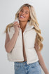 Woman wearing a cream sherpa vest against a white background
