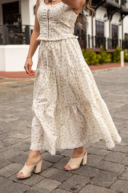 Woman wearing a white floral dress on a paved street.