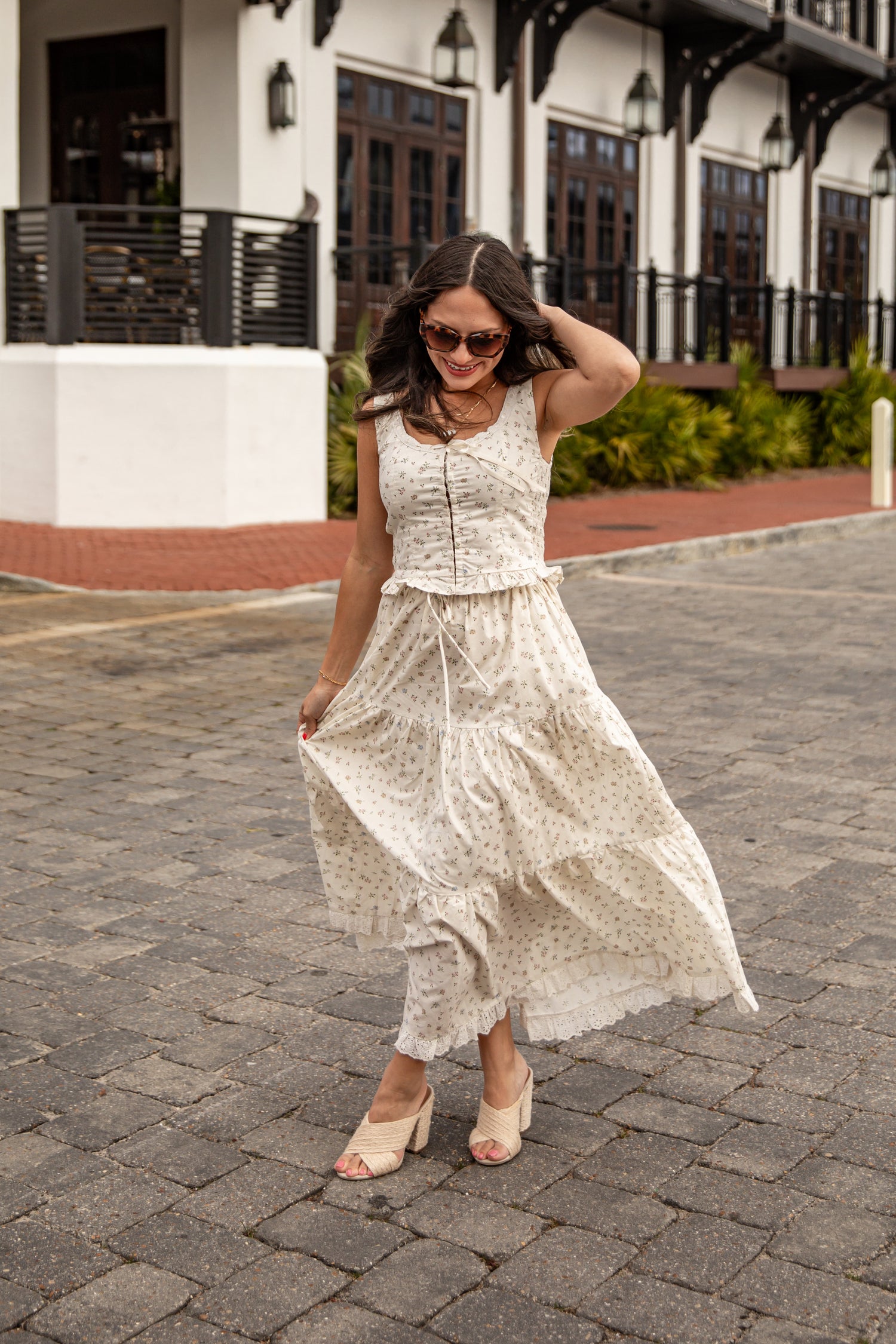 Woman in a white lace dress walking on a paved street.
