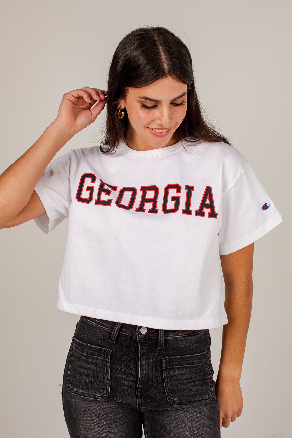 A woman wearing a white cropped t-shirt with &