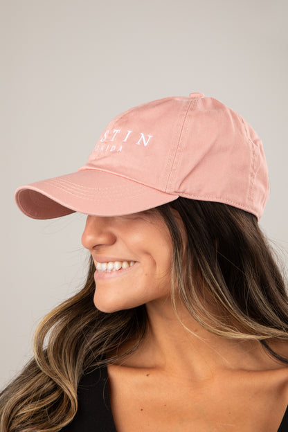 Person wearing a pink cap with text on a neutral background