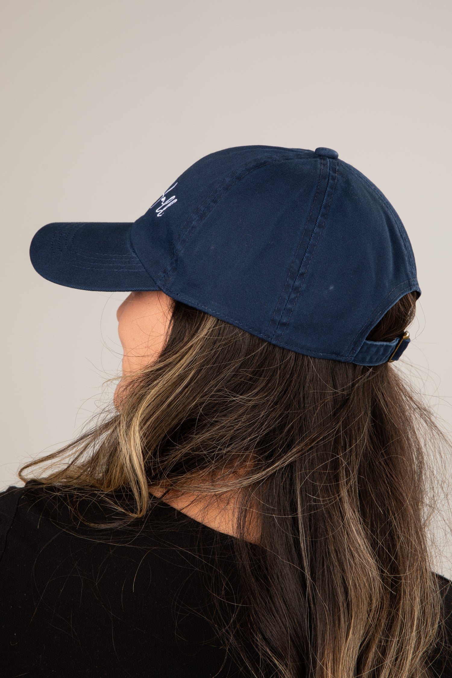 Person wearing a navy blue cap with a logo on a plain background