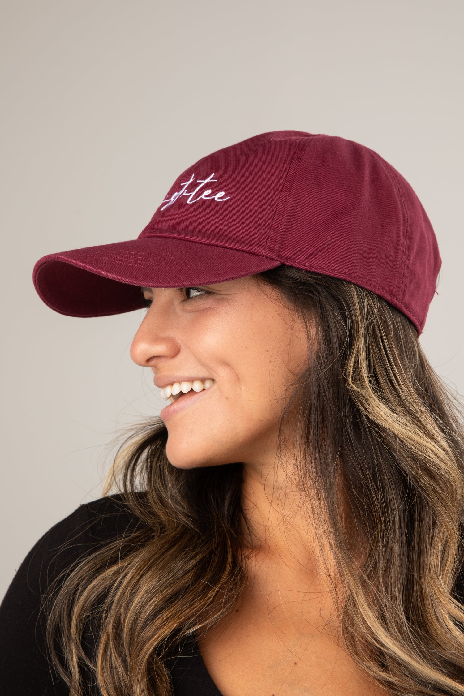Woman wearing a maroon cap with &