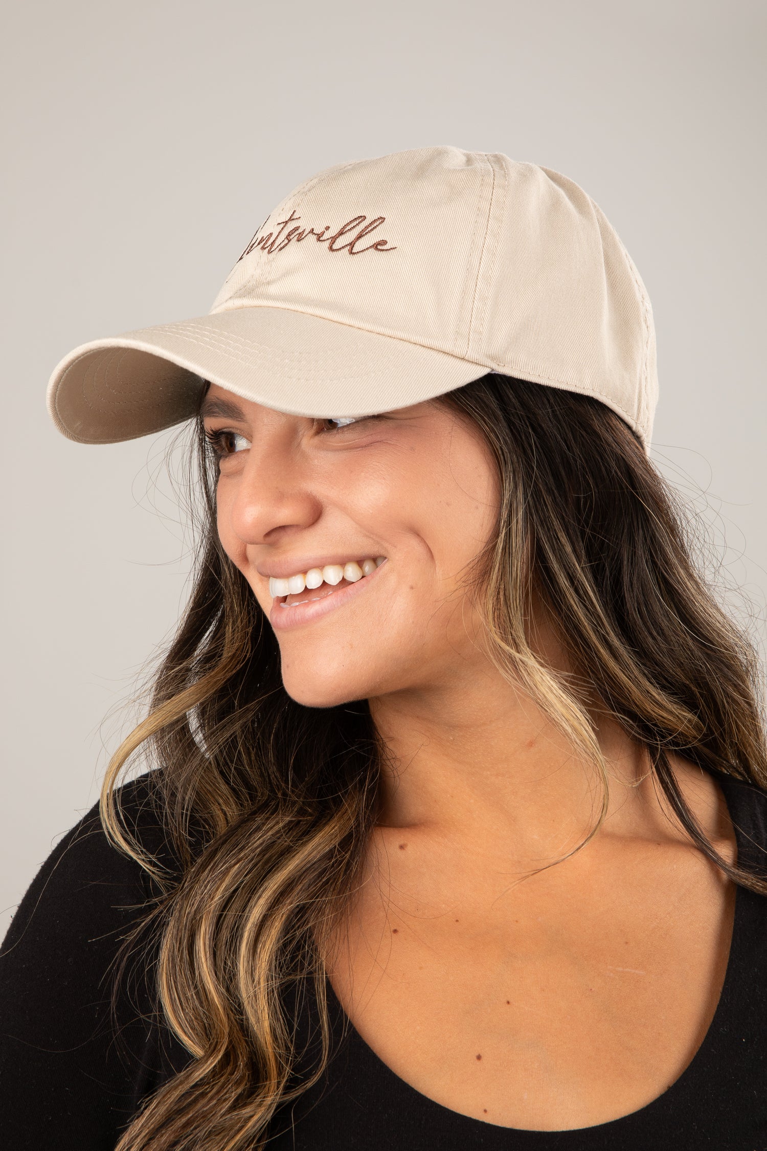 Woman wearing a beige cap with text on a plain background