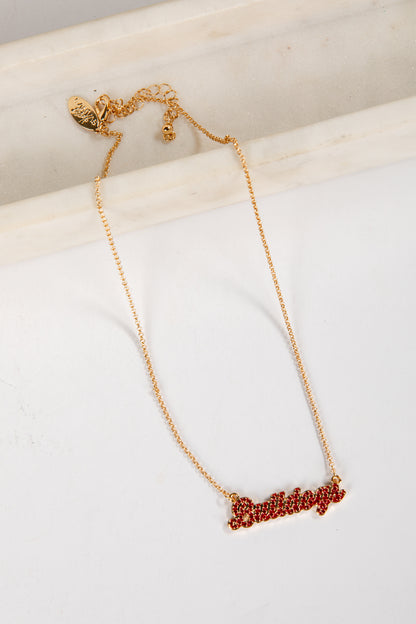 Gold necklace with red lettering on a white surface