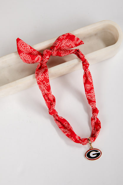 Red bandana-style necklace with a pendant on a light gray background
