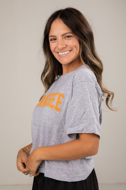 Woman wearing a gray t-shirt with orange text on a plain background
