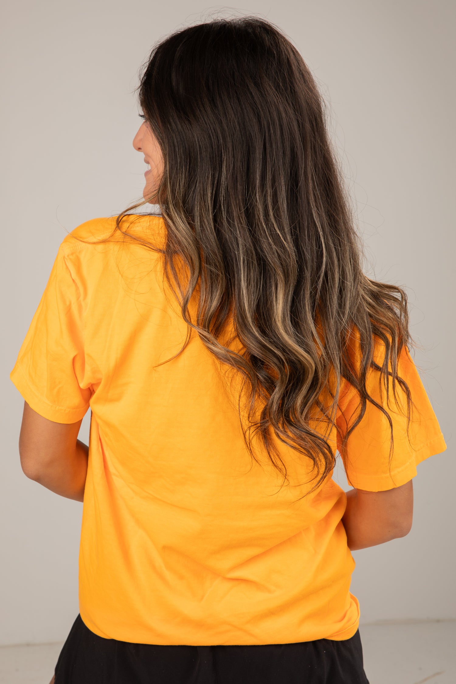 Person wearing a yellow shirt with a neutral background