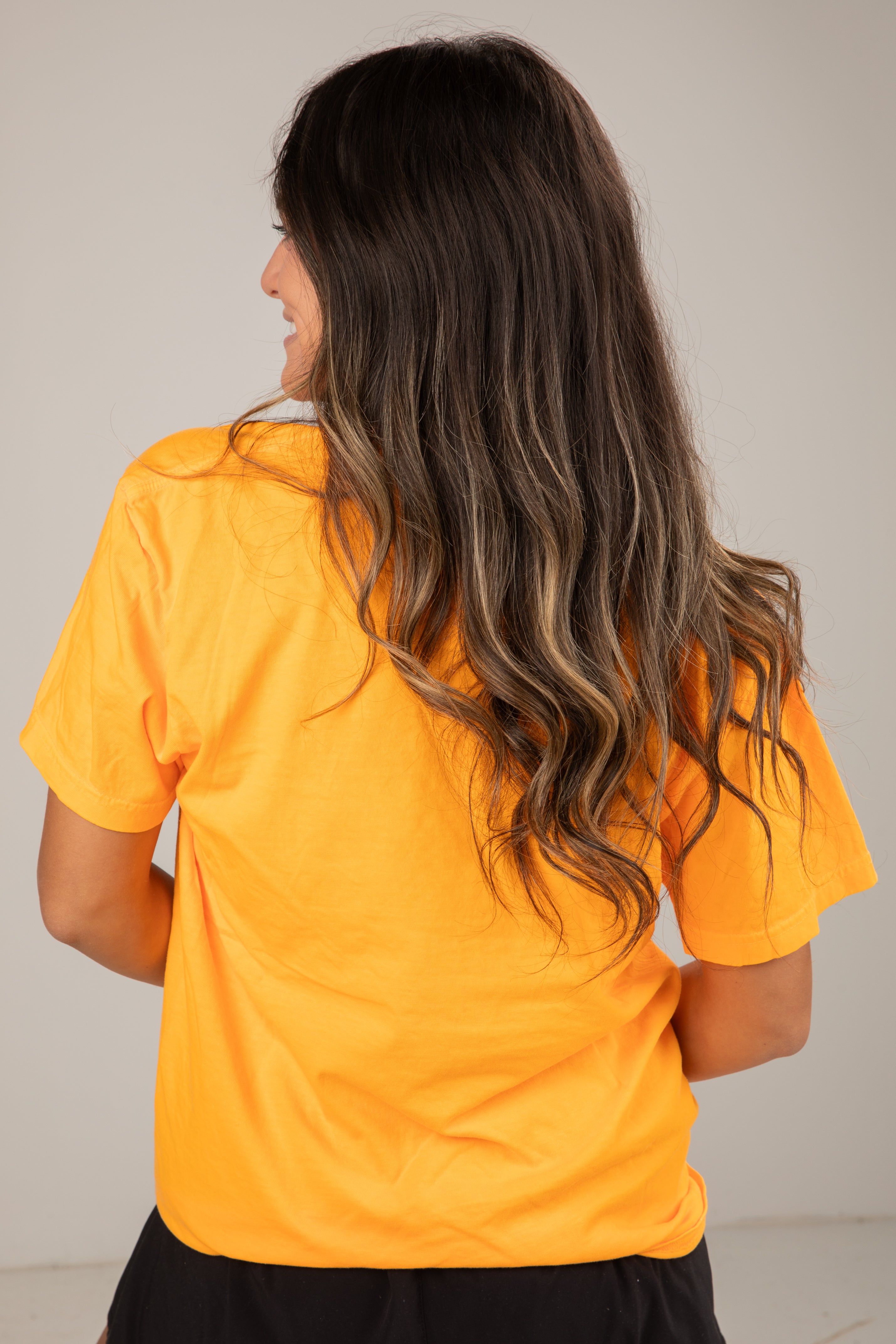 Person wearing a yellow shirt with a neutral background