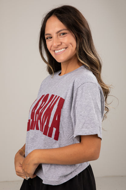 Woman wearing a gray t-shirt with red text on a plain background