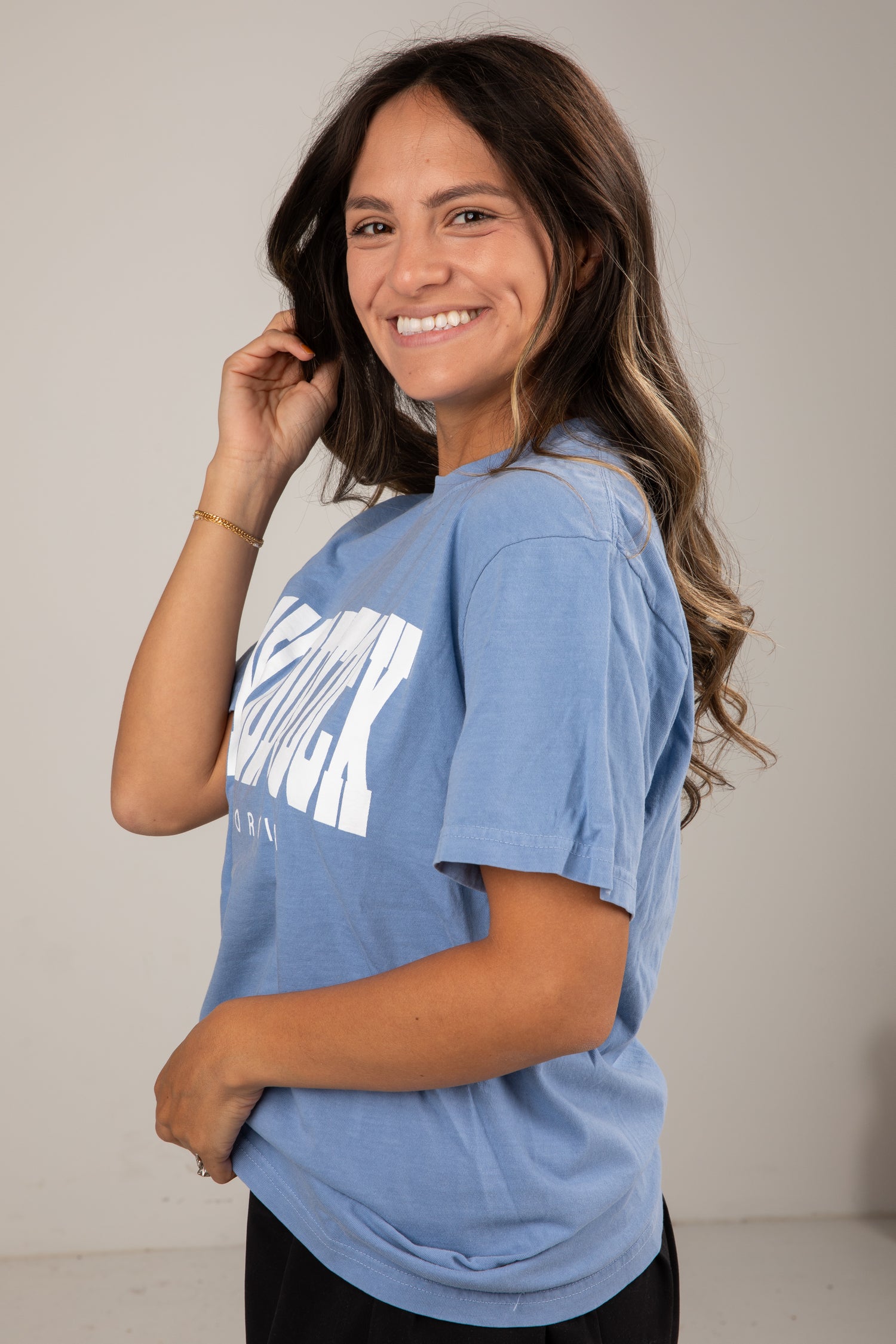 Woman wearing a blue t-shirt with text on a plain background