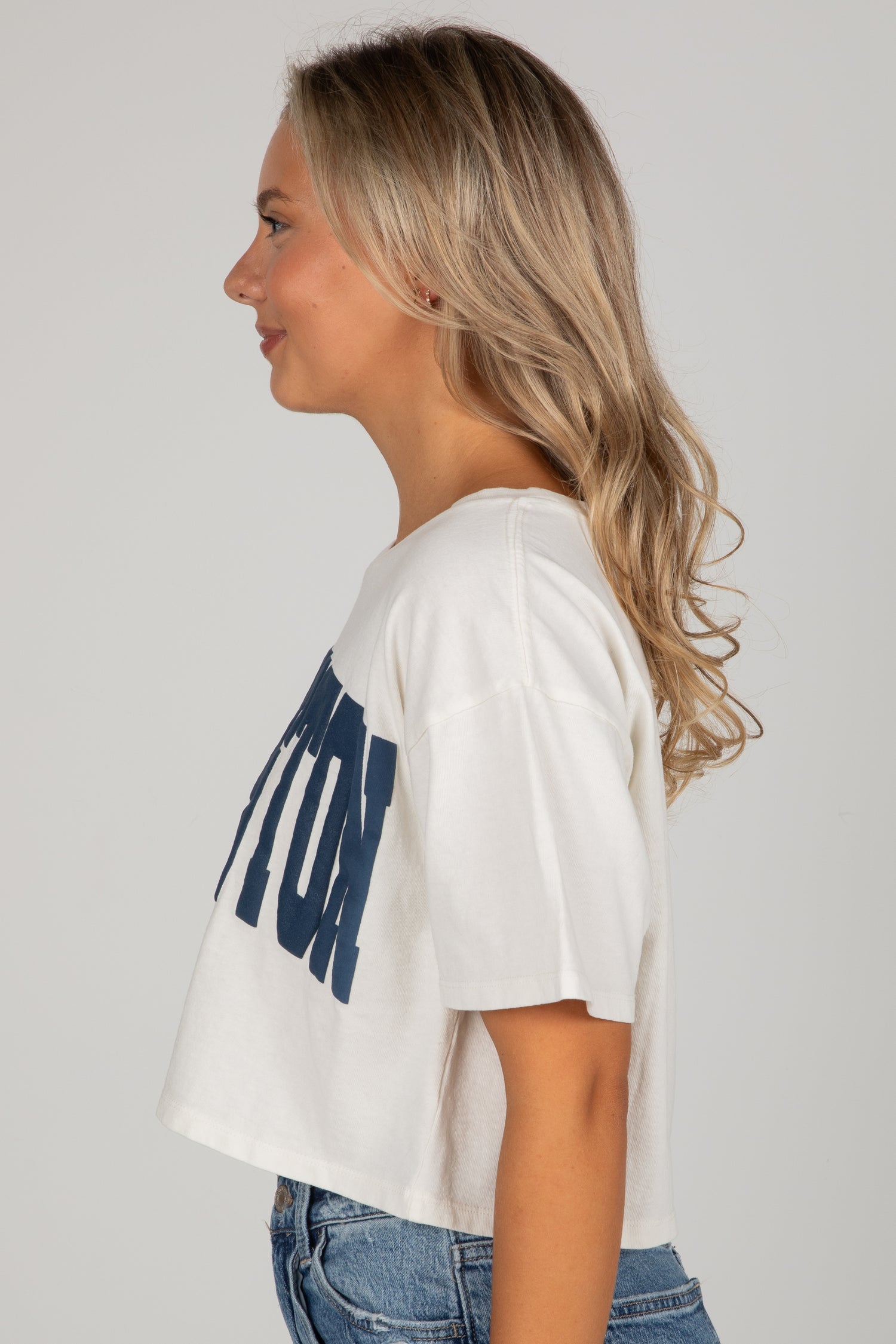 Woman wearing a white t-shirt with blue text on a plain background