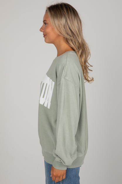 Person wearing a green sweatshirt with text on a plain background