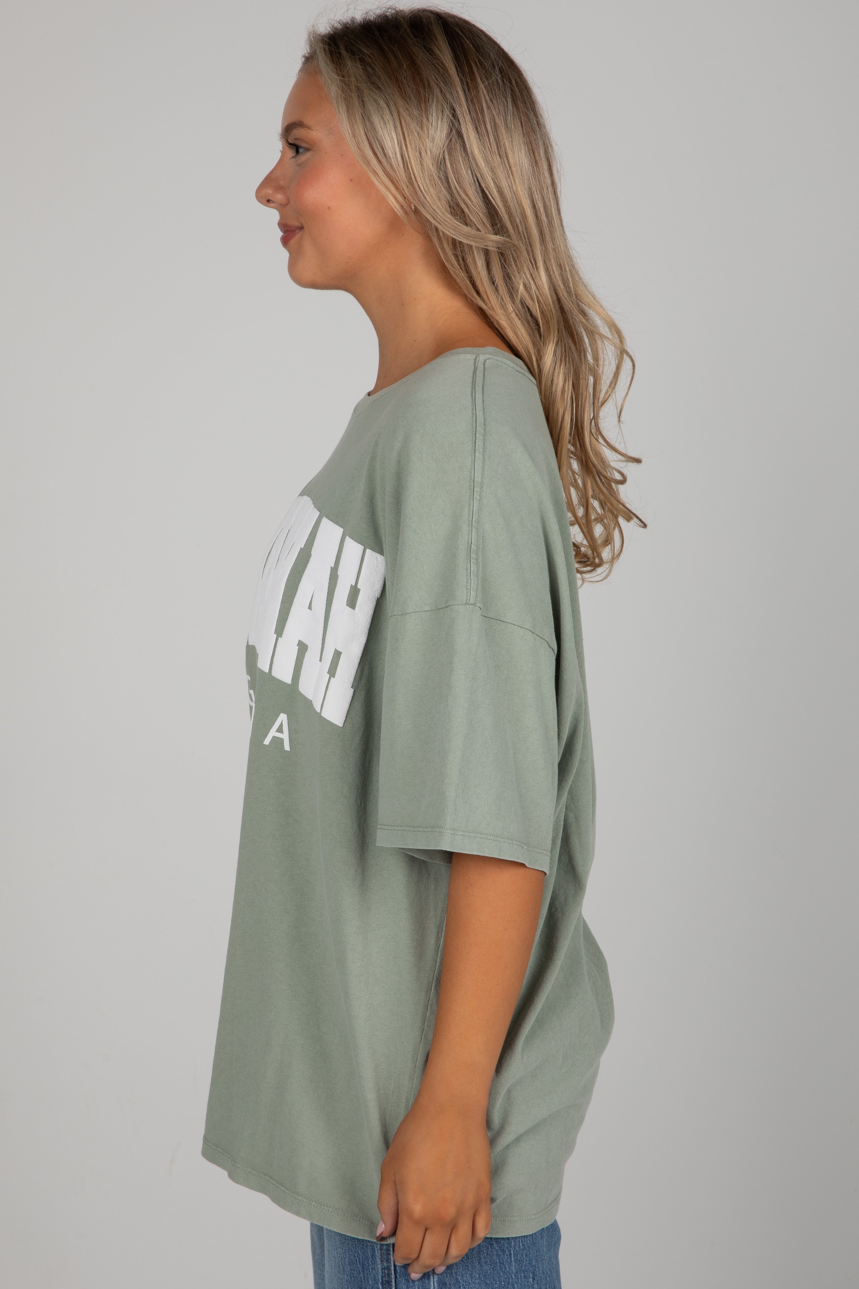 Woman wearing a green oversized t-shirt with text on a plain background