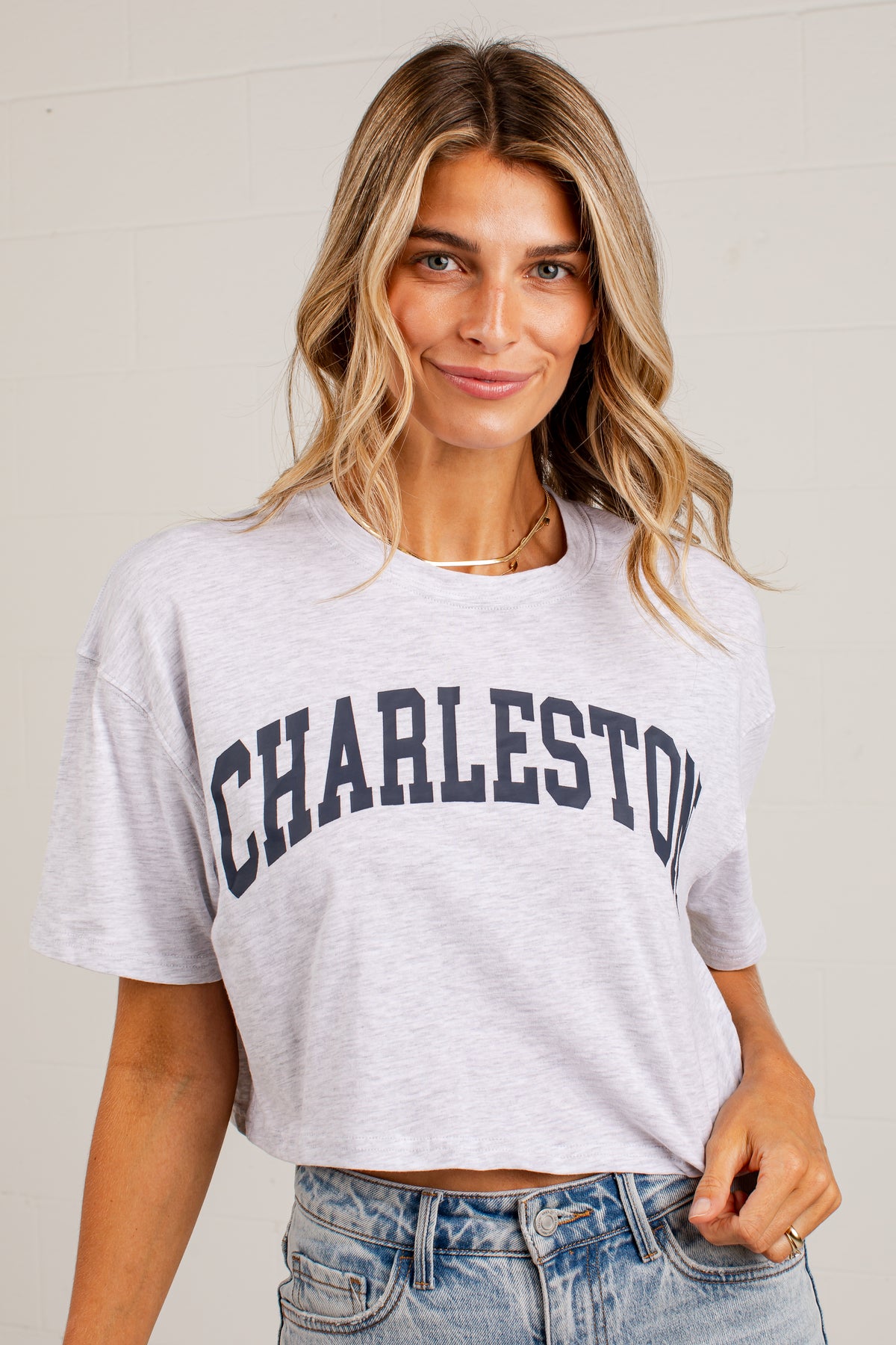 A woman wearing a light heather gray cropped t-shirt with &