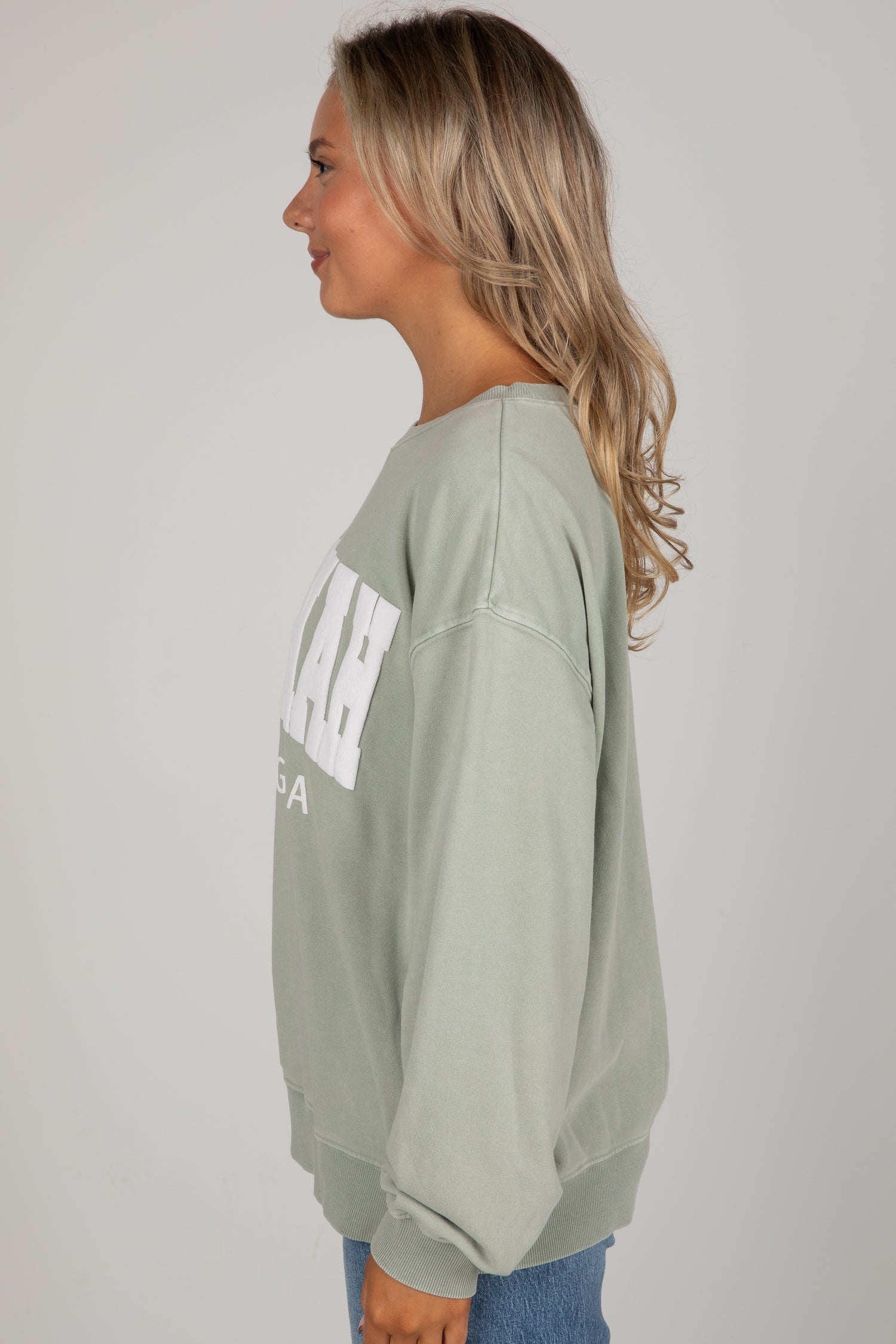 Woman wearing a green sweatshirt with text on a plain background