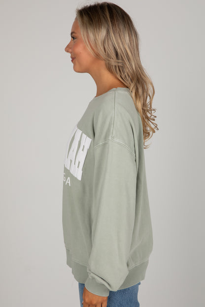Woman wearing a green sweatshirt with text on a plain background