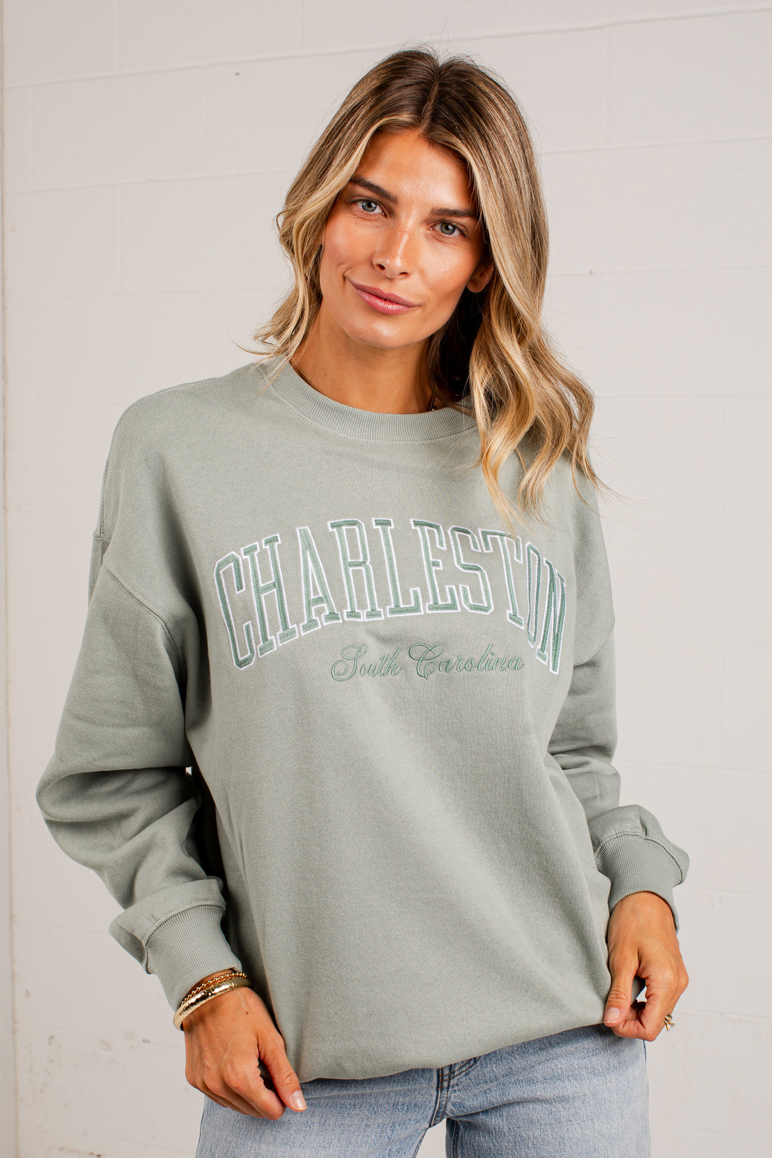 A woman wearing a sage green sweatshirt with &