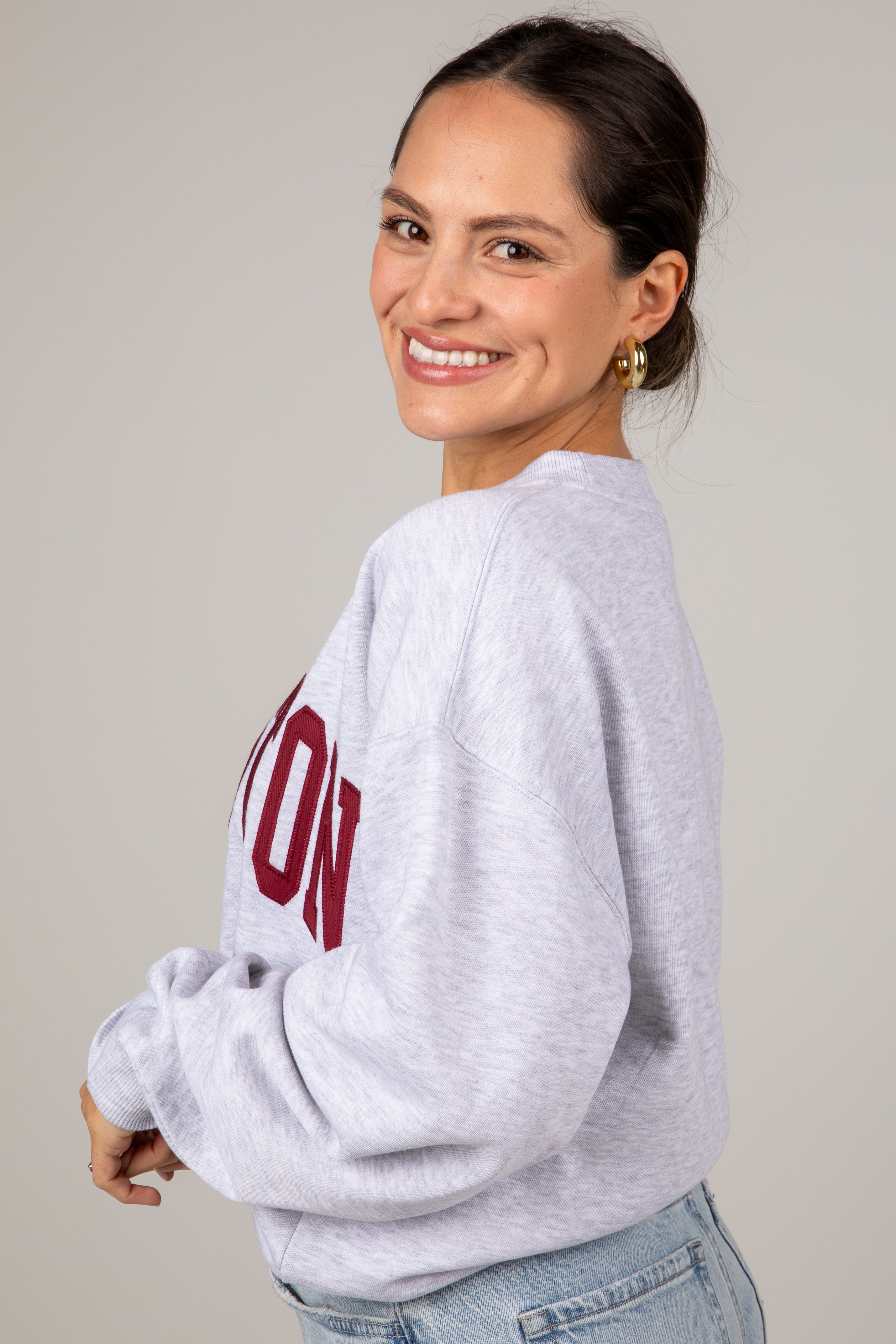 Woman wearing a gray sweatshirt with red text on a plain background