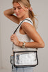 A woman wearing a white tank top and light blue jeans carries a clear plastic zippered shoulder bag with black trim and strap, photographed against a plain light gray wall.