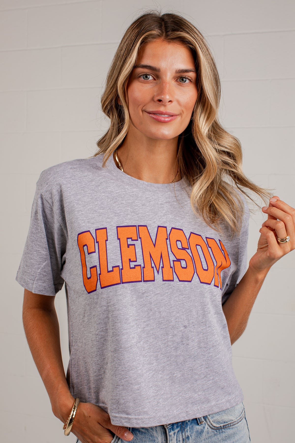 A woman wearing a heather gray Clemson Tigers graphic t-shirt with &