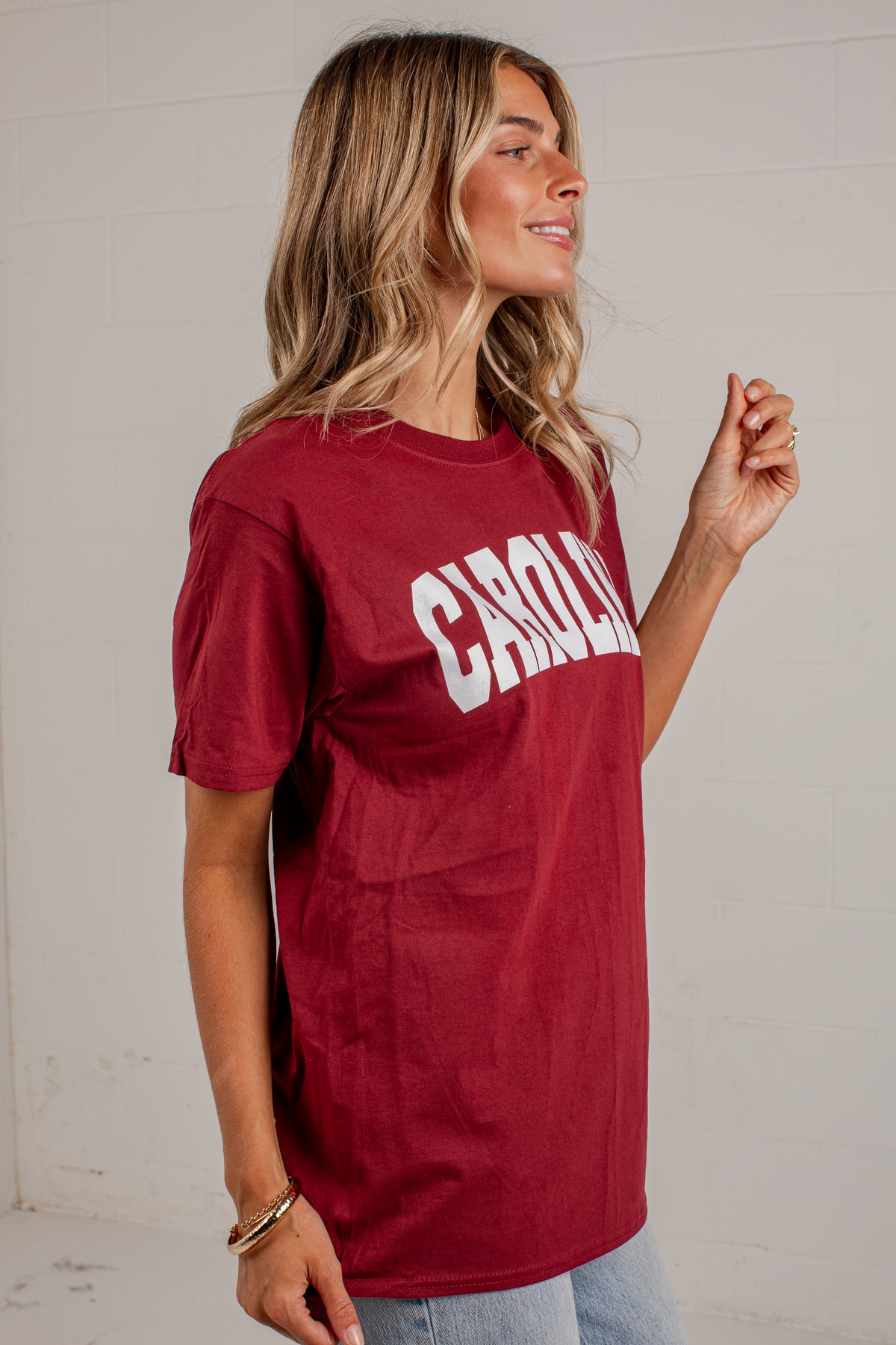 A woman wearing a maroon short-sleeve graphic t-shirt with &