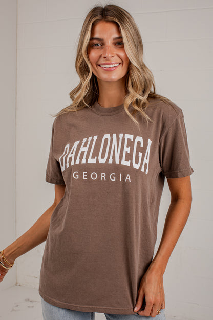 A woman wearing a brown short-sleeve graphic t-shirt with &