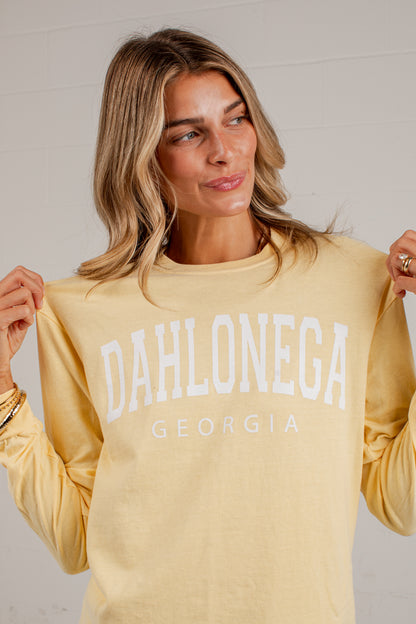 A woman wearing a pale yellow long-sleeve sweatshirt with &