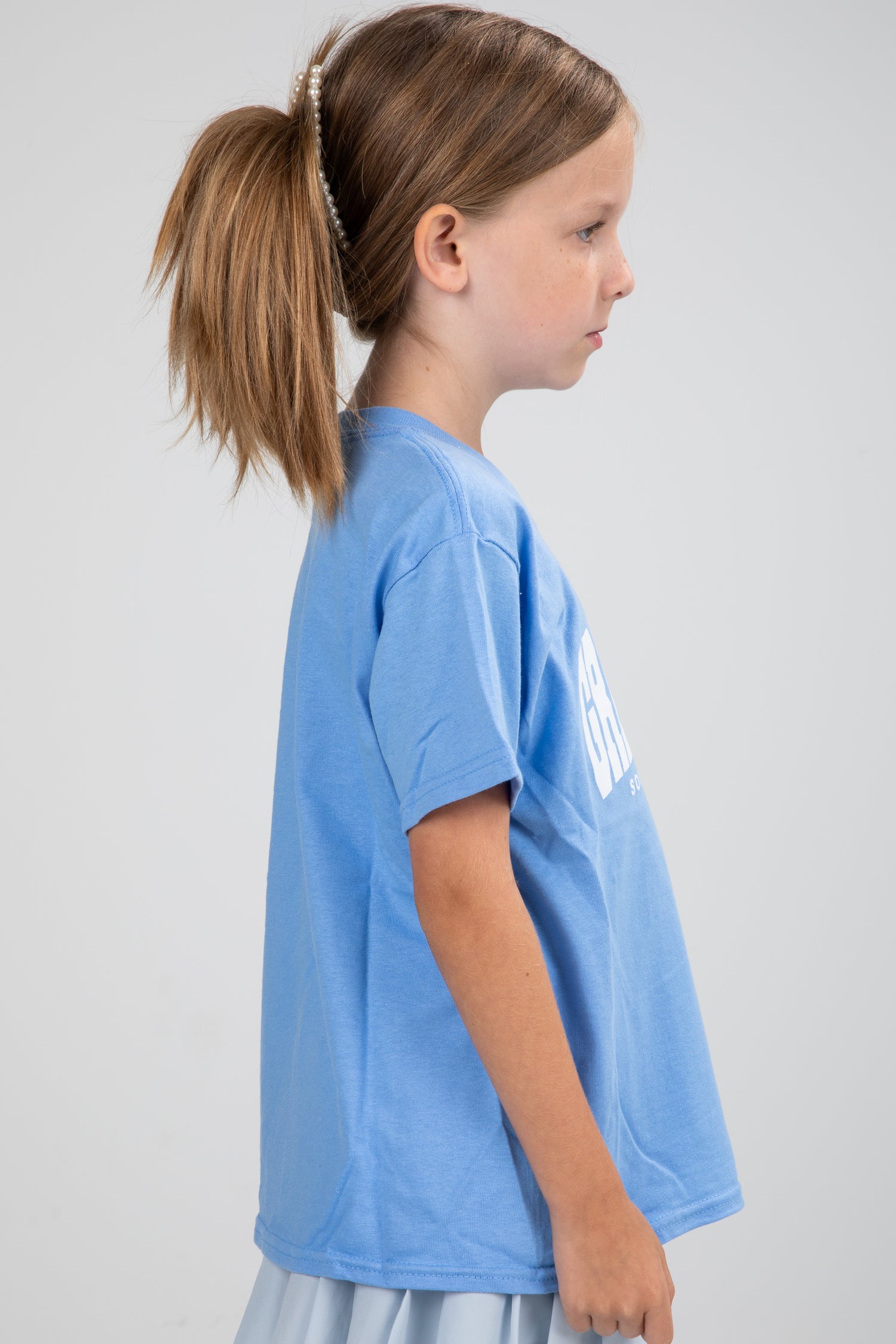 Young girl wearing a blue t-shirt with text on a plain background