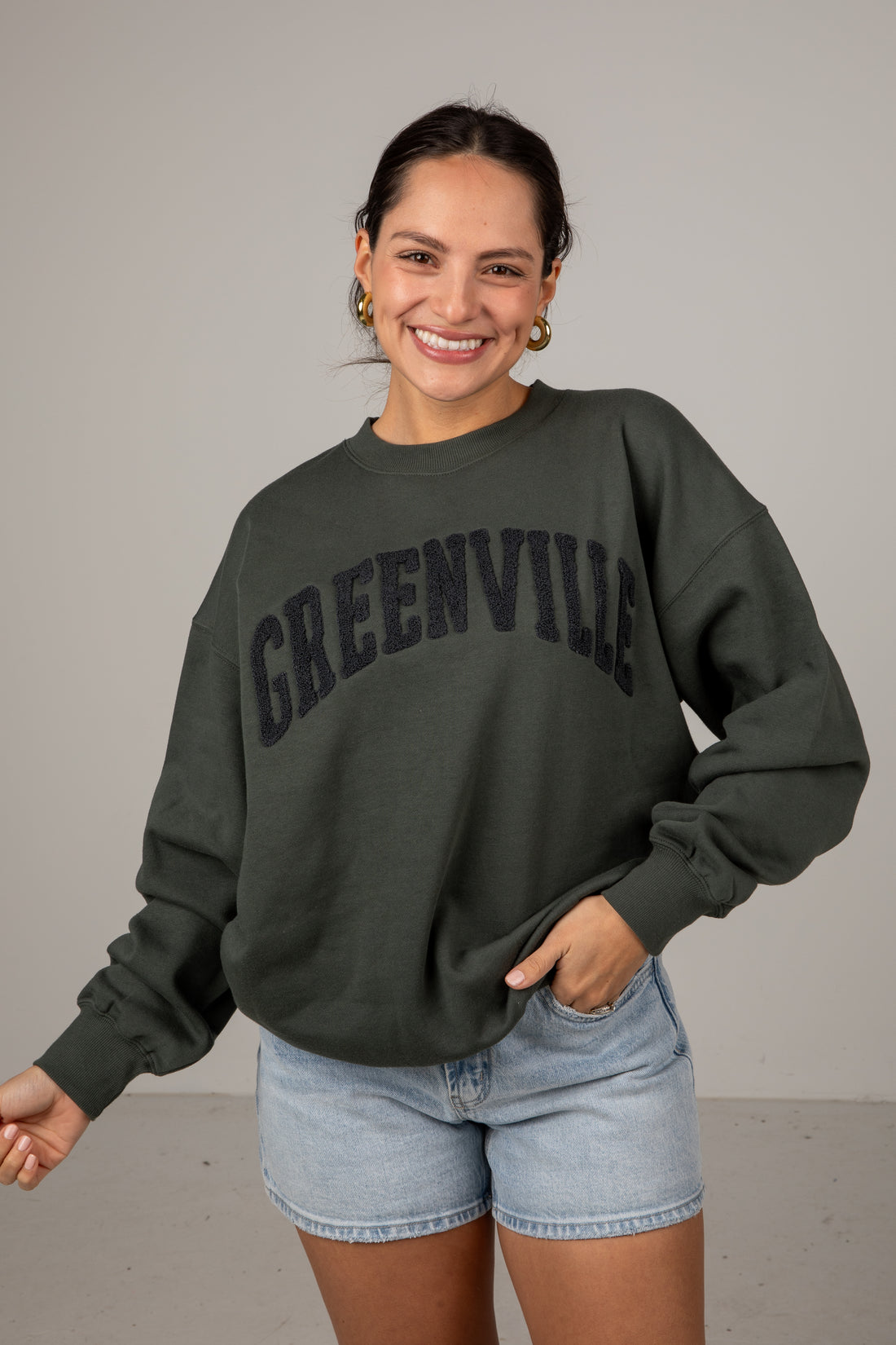 Woman wearing a dark green sweatshirt with &