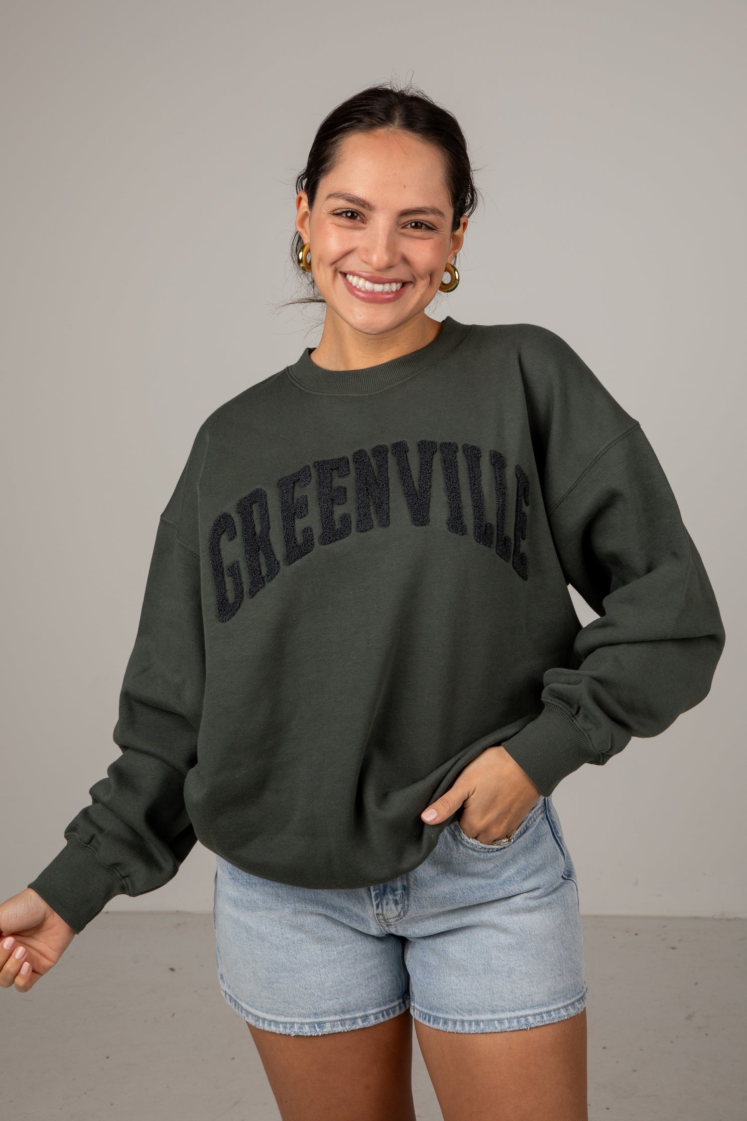 Woman wearing a dark green sweatshirt with &