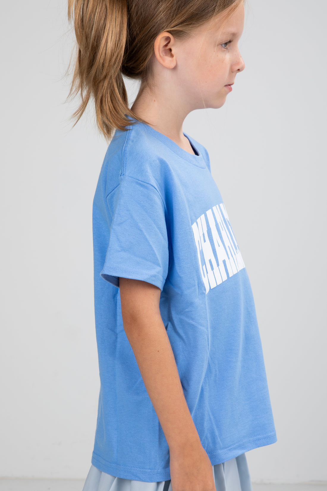 Child wearing a blue t-shirt with white text on a plain background