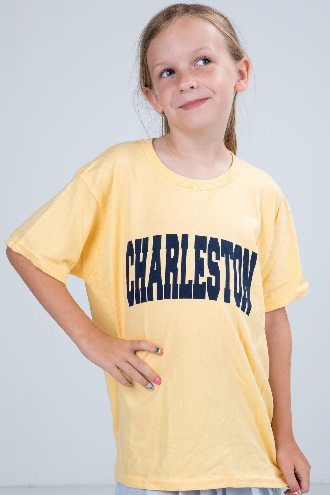 Young girl wearing a yellow t-shirt with &