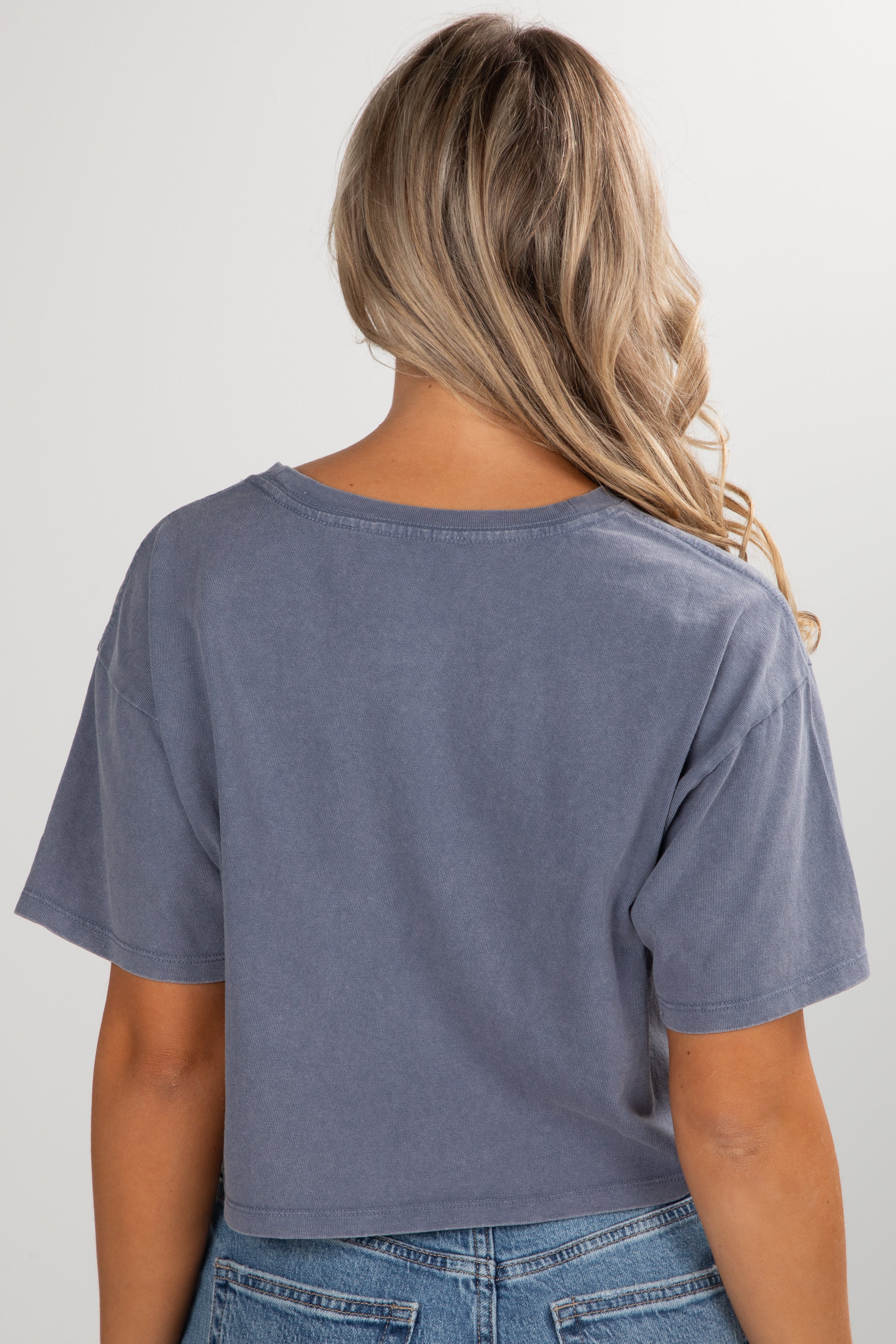 Person wearing a blue t-shirt and jeans on a plain background