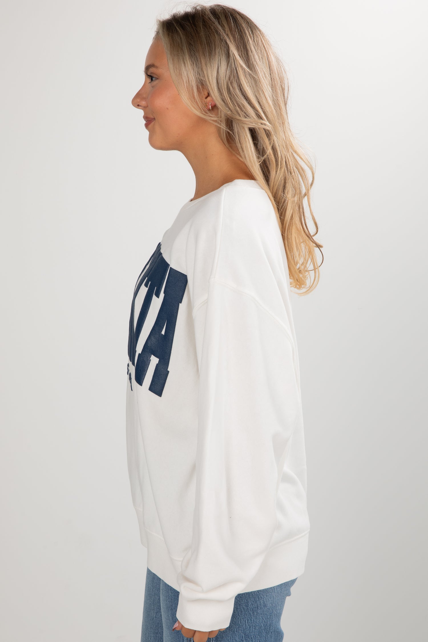 Person wearing a white sweatshirt with blue text on a plain background