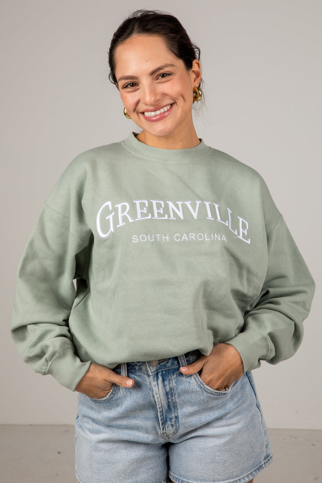 Woman wearing a green sweatshirt with &