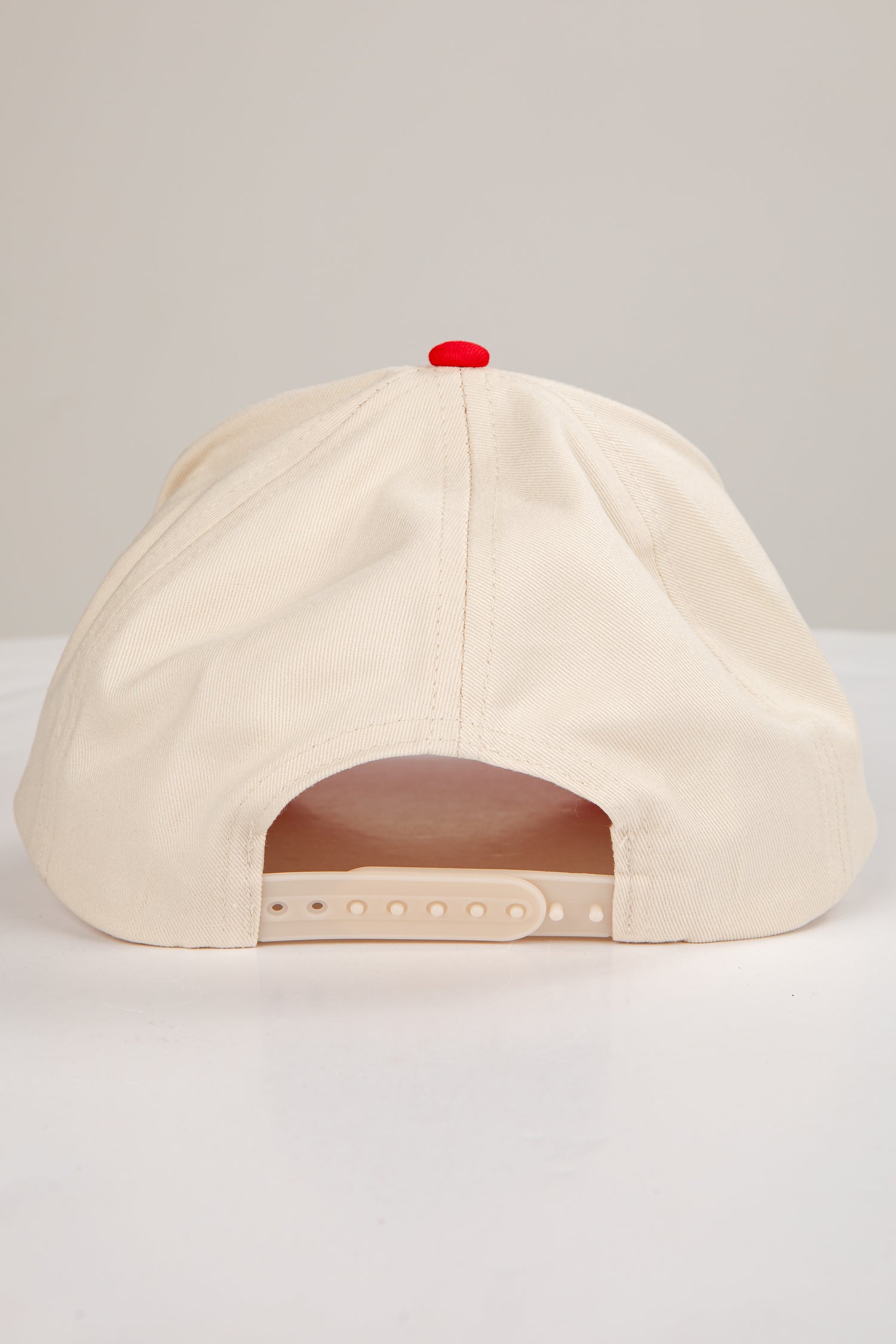 Beige cap with a red button on a light gray background