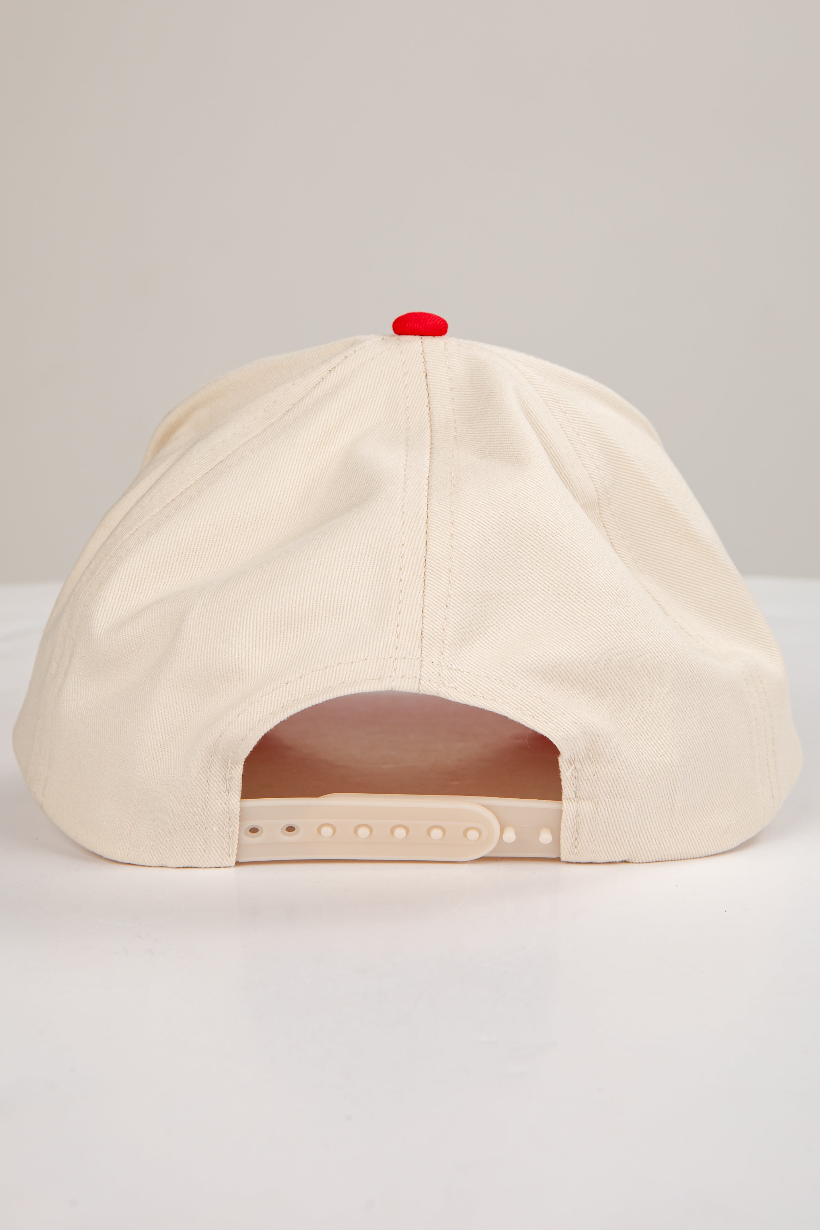 Beige cap with a red button on a light gray background