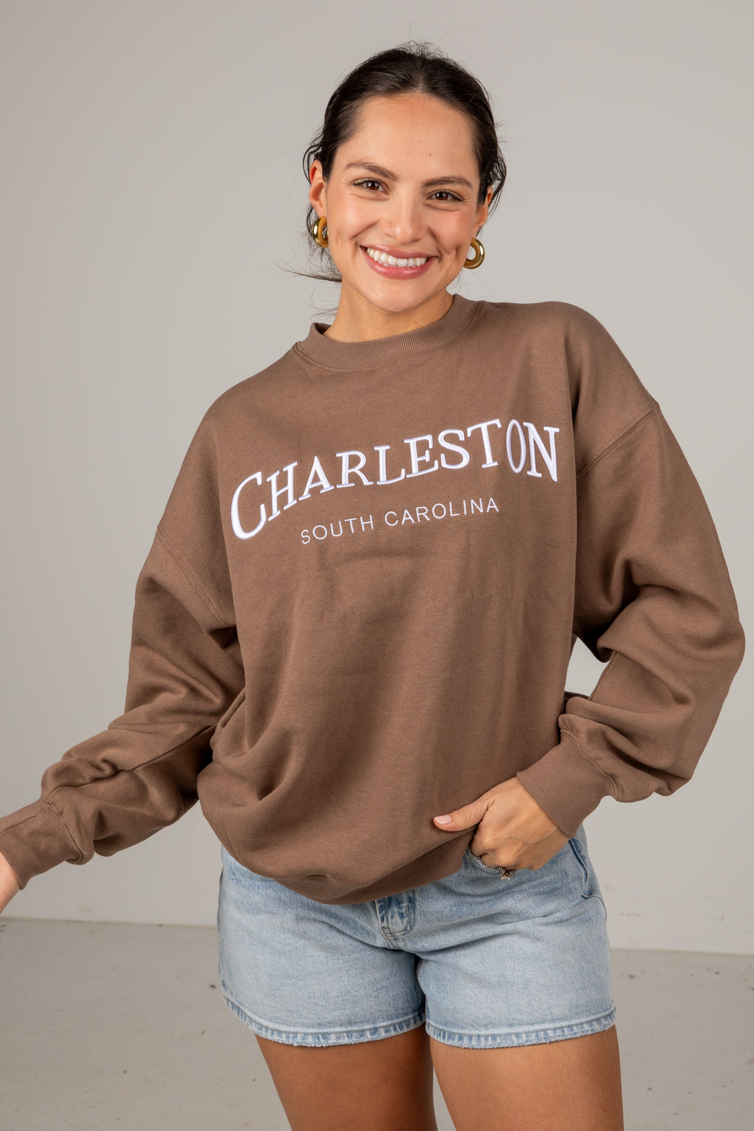 Woman wearing a brown sweatshirt with &