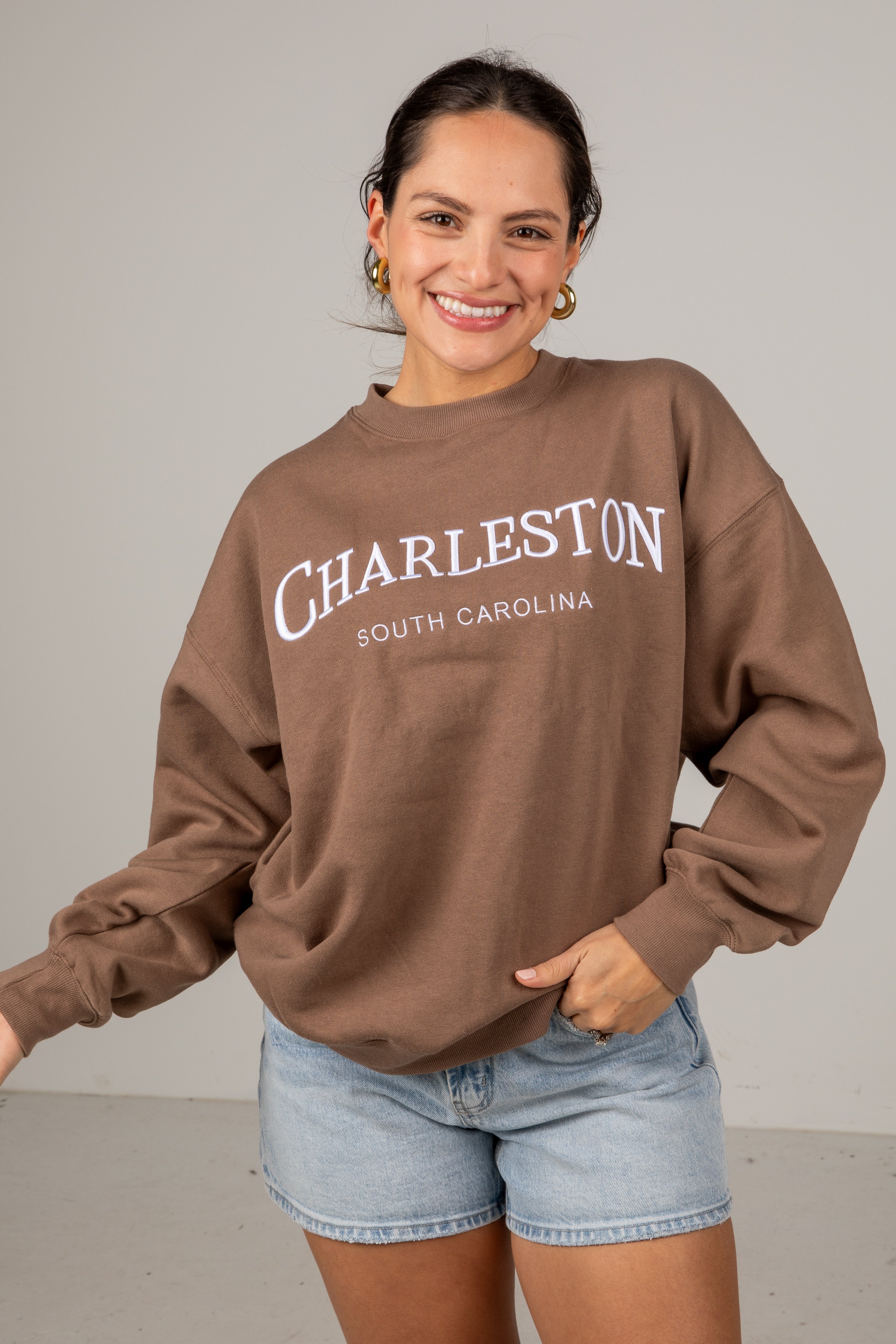 Woman wearing a brown sweatshirt with &