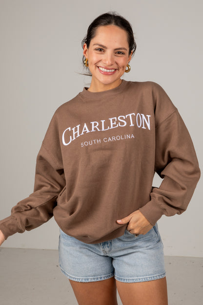 Woman wearing a brown sweatshirt with &