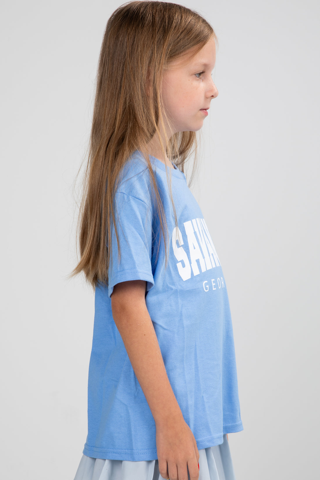 Young girl wearing a blue t-shirt with text on a plain background