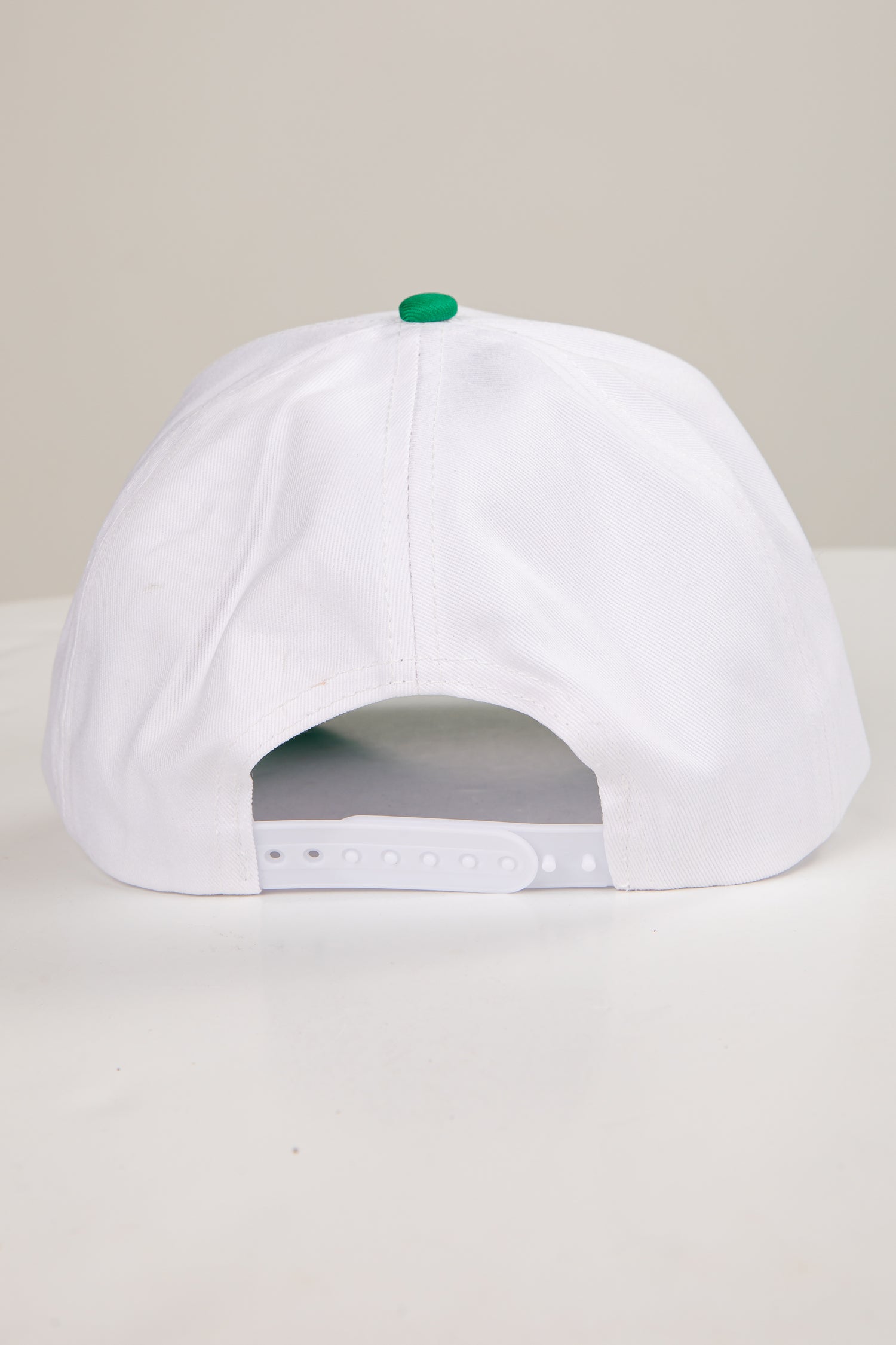 White cap with a green button on a light gray background